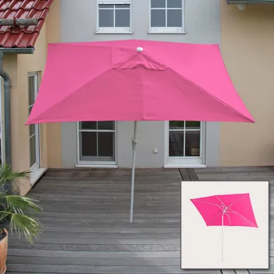 A pink rectangular umbrella is set up on a wooden deck in front of a house with windows.