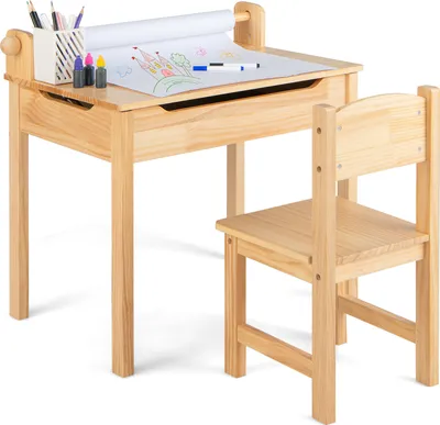 A wooden children's desk and chair set with a roll of paper and art supplies on the desk.
