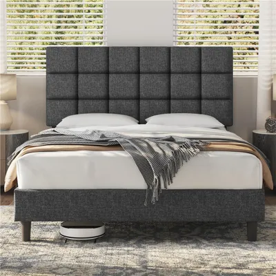 A dark gray upholstered bed frame with a tufted headboard is shown in a bedroom setting with blinds in the background.