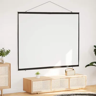 A white projection screen is hung on a white wall above a wooden media console with a small plant and a portable speaker on top.