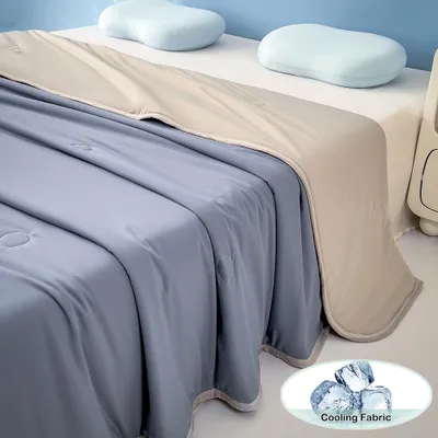 A bed with a blue and beige cooling blanket and two light blue pillows.
