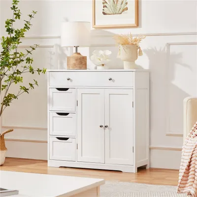A white cabinet with drawers and doors, decorated with a lamp, a plant, and a vase.