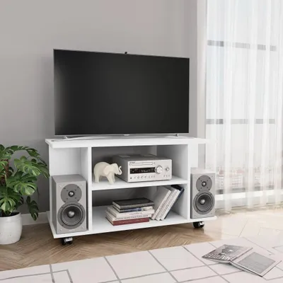 A white TV stand with a TV, speakers, and electronic equipment on it, placed in a room with a gray wall and a window with sheer curtains.