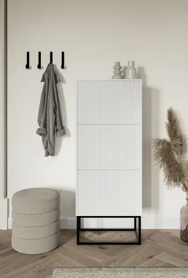 A white shoe cabinet with a black metal frame is shown in a minimalist room setting with a coat rack and a stool.