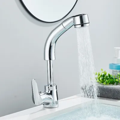 A chrome faucet with water running into a sink, with a mirror and some greenery in the background.