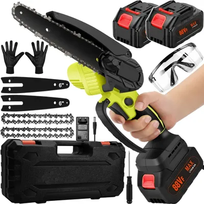 A hand holding a cordless chainsaw with accessories laid out around it.