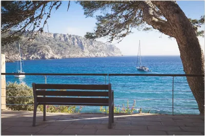 Produktbild von Wallario Wandbild Einsame Bank am Meer - Spanien im Sommer, Größe: 61 x 91,5 cm, Poster mit rahmenlosen Bildhalter