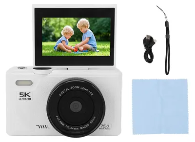 A white digital camera with its screen flipped up, displaying a picture of two children playing. Accessories like a USB cable and a cleaning cloth are placed next to it.