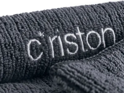 Close-up of embroidered text on a textured gray fabric.
