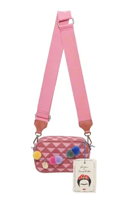A pink crossbody bag with a geometric pattern and colorful pom-pom decorations, shown hanging with its strap and a product tag.