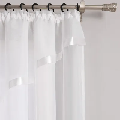 A close-up view of white sheer curtains hanging from a curtain rod.