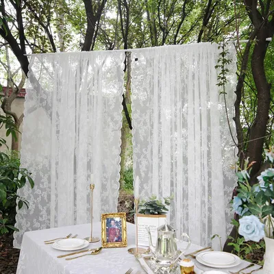 A table setting outdoors with white lace curtains in the background.