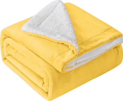 A folded yellow blanket with a white sherpa lining is shown.