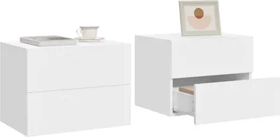 Two white nightstands are shown, one with a book and cup on top, the other with a drawer open and a framed picture on top.