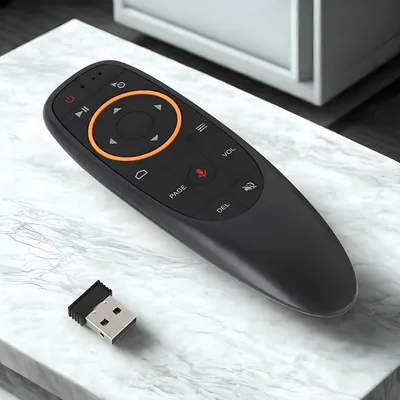 A black remote control and a USB dongle are placed on a marble surface.