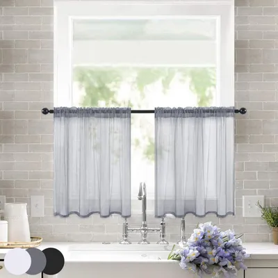 A kitchen sink area with a window covered by two grey sheer curtains.