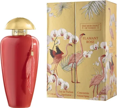 A red perfume bottle with a gold cap and a decorative tassel sits next to its matching packaging box, which features a design of flamingos and orchids on a gold background.