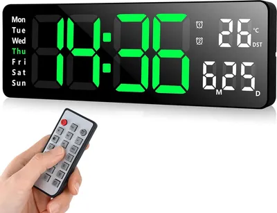 A hand holding a remote control in front of a digital clock.