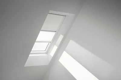 A skylight with a white roller blind and a white pleated blind inside a white room.