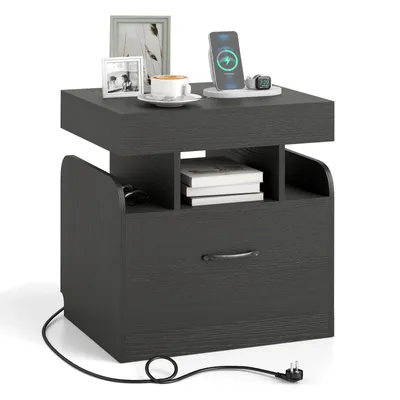 A dark gray nightstand with a drawer and open shelves, featuring a wireless charger, a cup of coffee, and picture frames on top.