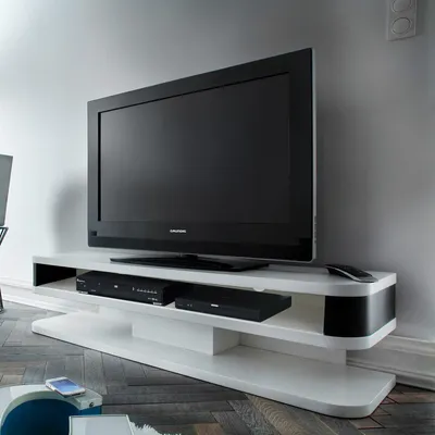 A modern TV stand with a TV and media devices on it, in a room.