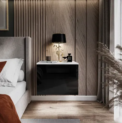 A bedside table with a lamp and decorative items next to a bed in a bedroom.
