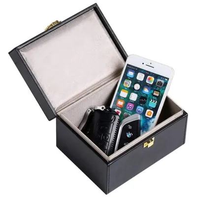 An open black box containing a smartphone and car keys.