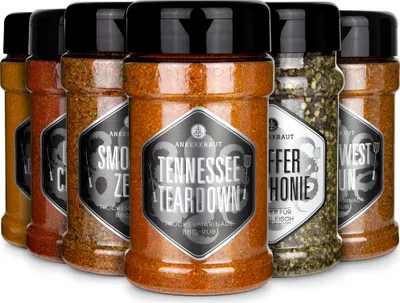 A set of six spice jars with black lids and labels, arranged in a row.