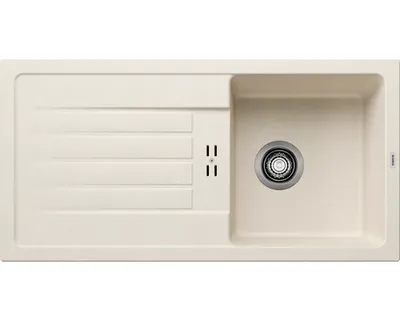 A top-down view of a cream-colored kitchen sink with a drainboard and a stainless steel drain.