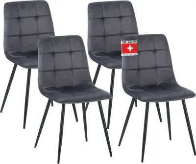 Four dark gray upholstered dining chairs with black metal legs are arranged in a group against a white background. One chair has a red and white tag attached to its back.