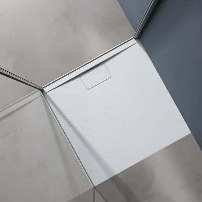 A close-up, angled view of a white shower tray with a textured surface, set against gray walls.