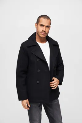 A man wearing a black pea coat and jeans against a white background.