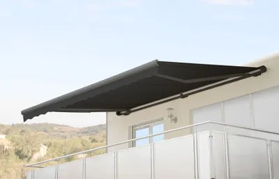 A black retractable awning is extended over a balcony on a building.