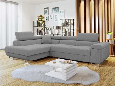 A modern living room with a gray sectional sofa, a white coffee table, and decorative shelves.