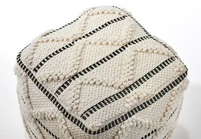 A close-up view of a white pouf with black geometric patterns.