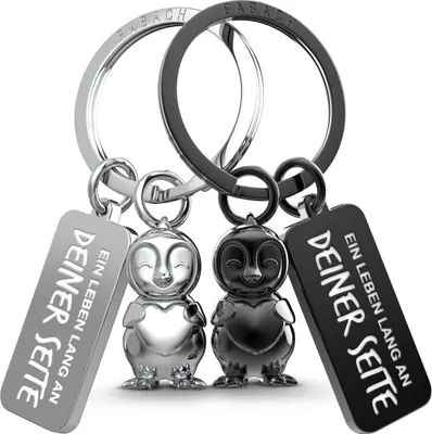 Two penguin-shaped keychains, one silver and one black, are displayed against a white background.