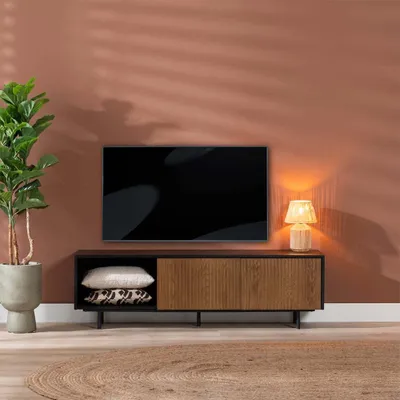 A TV stand with a television, a lamp, and a plant in a living room setting.