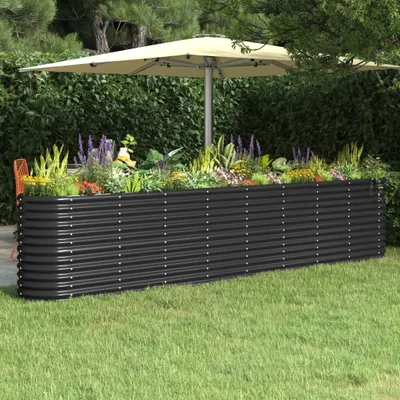 A raised garden bed filled with plants in a garden setting, with a patio umbrella in the background.