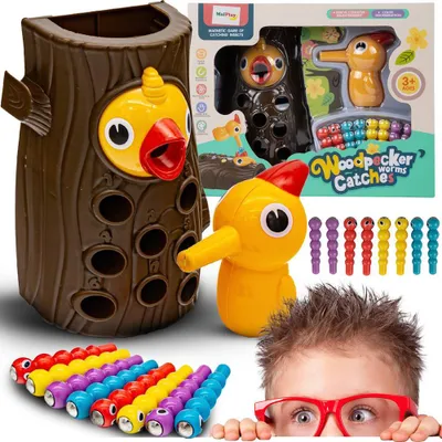 A collection of toys, including a wooden tree-like structure with holes, a yellow woodpecker toy with a magnetic beak, and colorful worm-shaped toys, arranged with a child peeking from the bottom.