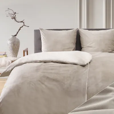 A neatly made bed with taupe bedding and pillows, set against a neutral background.