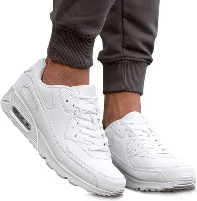 A pair of white sneakers worn by a person, shown from the ankle down.