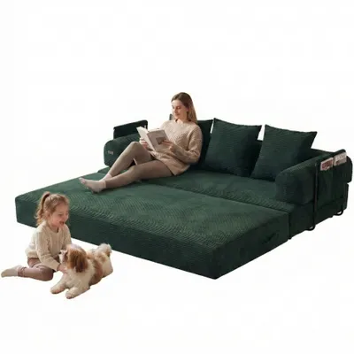 A woman reads a book on a green sofa while a child plays with a dog on the floor in front of it.