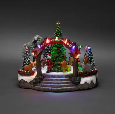 A festive Christmas zoo scene with Santa, animals, and a decorated tree under an archway.