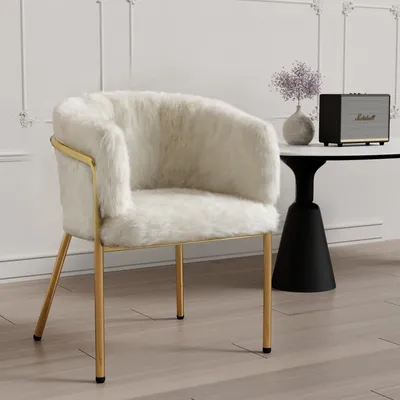 A fluffy white chair with gold legs is shown in a room with a small table and speaker.