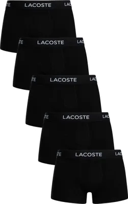 A stack of five black boxer shorts with the Lacoste logo on the waistband.