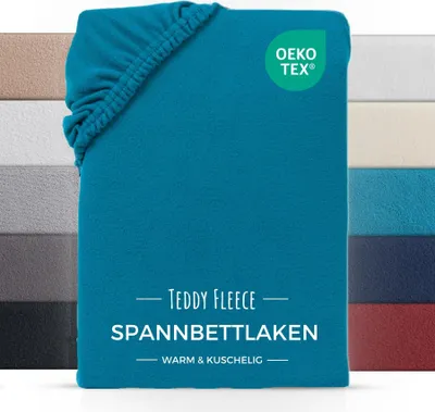 A teal colored fitted sheet is shown folded, with a stack of other colored fitted sheets visible on the left and right sides.