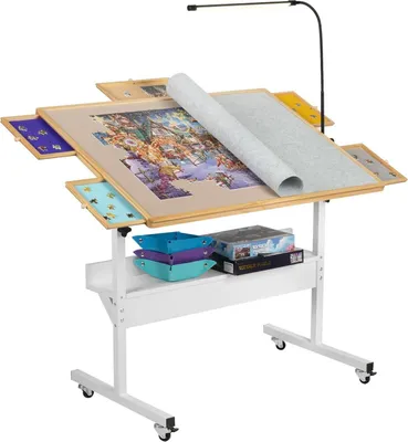 A puzzle table with a partially completed puzzle, a rolling mat, and storage drawers, set against a white background.