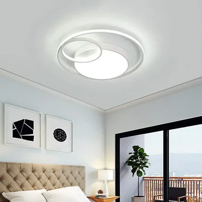 A modern bedroom with a bed, artwork on the wall, and a large window with a view.