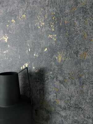 A close-up shot of a textured wall with gold accents and a black vase in the foreground.