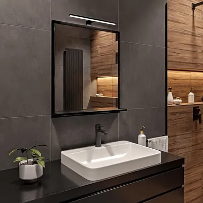 A modern bathroom vanity with a sink, faucet, mirror with integrated lighting, and a small potted plant.